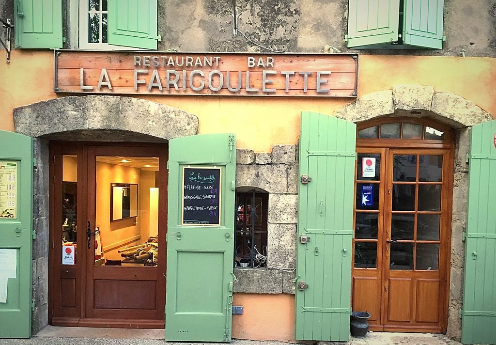 La devanture de La Farigoulette, volets verts et enseigne, place des Ormeaux à Tourtour